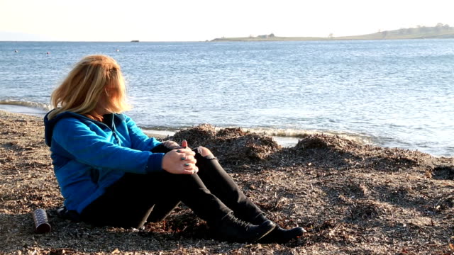 Mujer-triste-sentada-en-la-orilla-del-mar