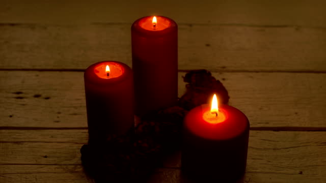 Red-candle-flame-and-roses-on-wooden-desk-romantic-theme