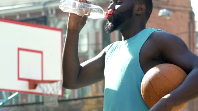 Afro-American-Basketball-Spieler-Trinkwasser-genießen-Sieg-seines-Teams