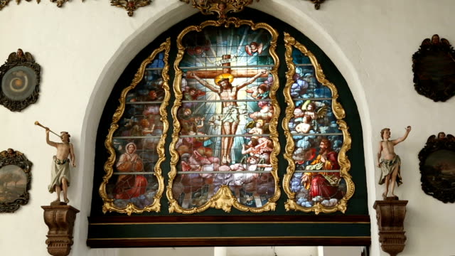 Stained-glass-window-with-crucified-Jesus-and-other-saints,-church-interior