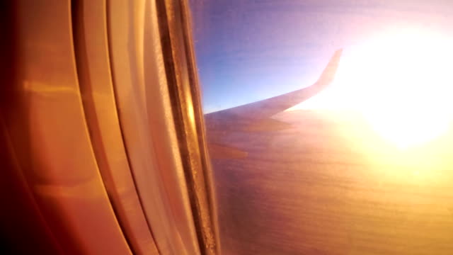 Blick-aus-dem-Fenster-eines-Passagier-Flugzeug-während-des-Sonnenuntergangs-auf-eine-Landschaft-und-Horizont