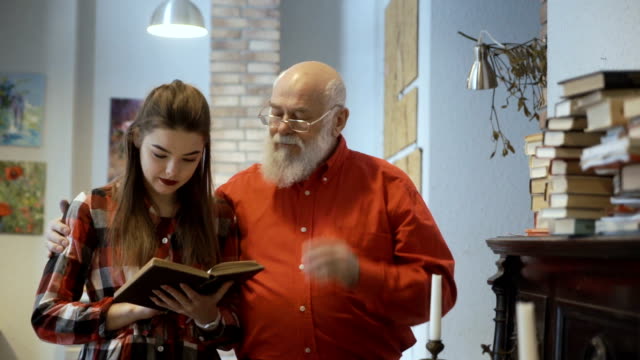 Young-pretty-girl-reads-interesting-book-together-with-grandfather