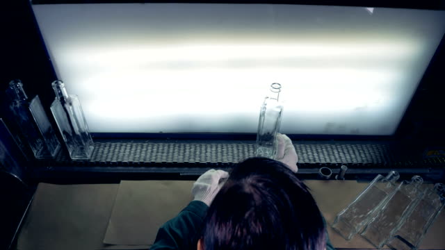 A-female-worker-checks-bottles-on-a-conveyor.