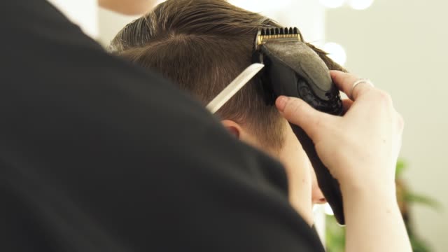 Hairdresser-using-electric-razor-for-male-haircut.-Close-up-hair-trimmer-for-male-hairstyle.-Professional-hairdresser-cutting-hair-with-clipper
