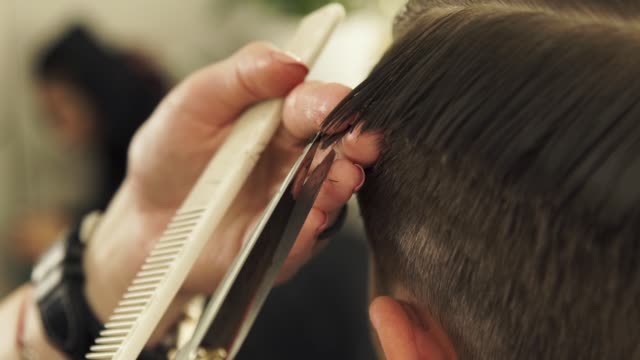 Haircutter-combing-hair-and-cutting-with-hairdressing-scissors-in-barbershop.-Close-up-hand-hairdresser-cutting-wet-male-hair-with-hairdressing-scissors-in-beauty-salon