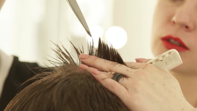 Cutting-hair-with-professional-scissors-in-hairdressing-salon-close-up.-Haircutter-cutting-hair-with-hairdressing-scissors-and-combing-in-barber-shop