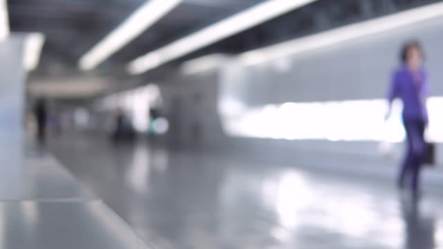 Blurred-footage-of-passengers-walking-through-the-walkway-corridor-to-airport-terminal.-4K-video-with-defocused-effect.