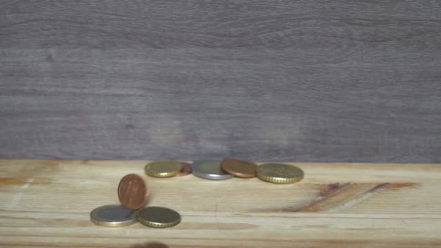 Business-concept---man-hand-collect-euro-coins-on-the-wooden-table.