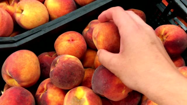 Young-man-picking-peaches-in-the-supermarket
