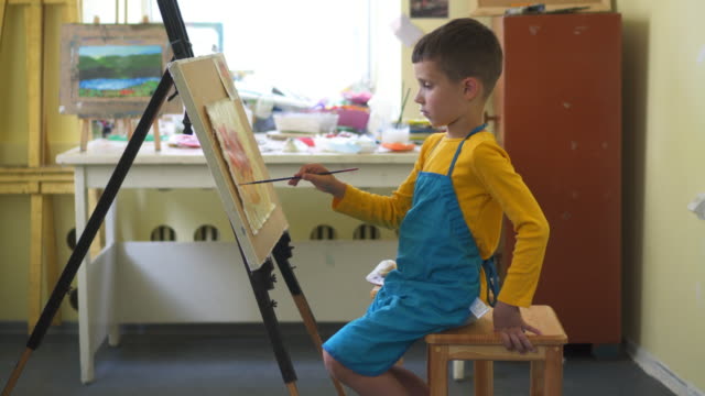Nachdenkliche-junge-Malerei-mit-Ölfarben-während-des-Unterrichts