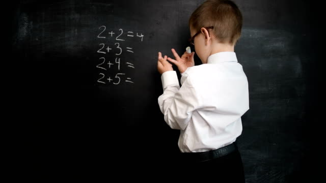 Junge-Mathe-Ausdruck-auf-einer-Tafel-zu-lösen.-Kreatives-Konzept-zurück-zu-Schule-und-Studium.-Vorschule