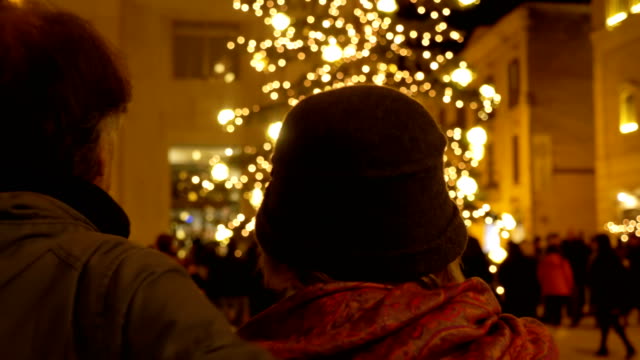 christmas-holiday:-mature-couple-looking-at-christmas-tree-in-town-square