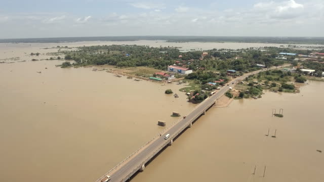 drone-:-flying-back-over-a-concrete-bridge-running-across-the-flooded-river-in-rural-area