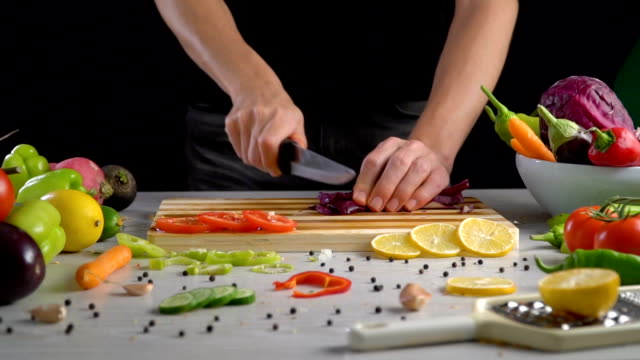 Man-is-cutting-vegetables-in-the-kitchen,-slicing-red-cabbage-in-slow-motion