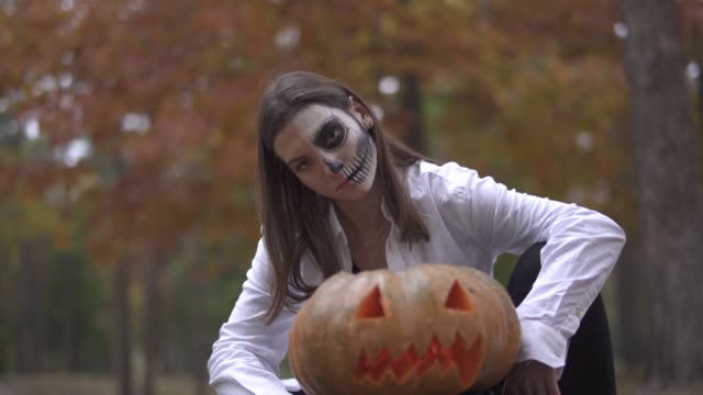 Halloween.-Eine-Mädchen-mit-einem-scary-Halloween-Make-up-sitzt-in-der-Nähe-der-Kürbis