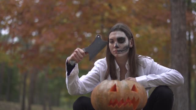Halloween.-Mädchen-mit-einem-scary-Halloween-Make-up-sitzt-mit-einem-Fleischermesser