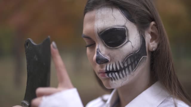 Halloween.-Girl-with-Halloween-make-up-runs-her-finger-along-the-blade-of-knife