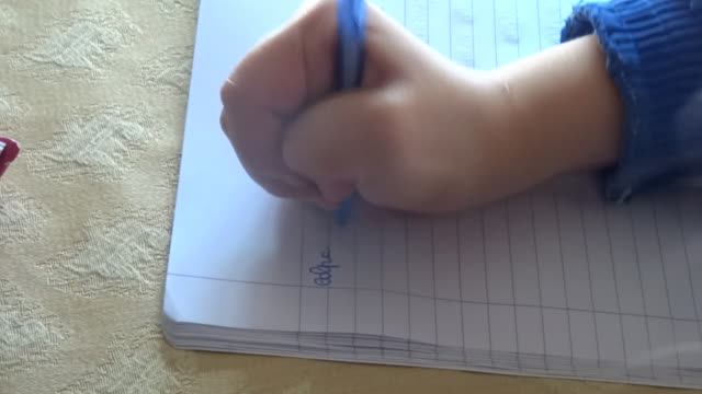Child-Hands-writing-on-the-book