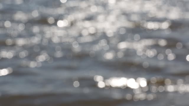Mesmerizing-bright-defocused-glares-from-the-sun-on-the-wavy-surface-of-the-water