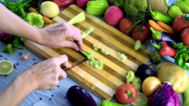 Man-is-cutting-vegetables-in-the-kitchen,-slicing-green-bell-pepper