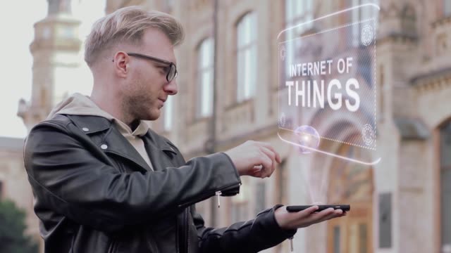 Kluger-junger-Mann-mit-Brille-zeigt-eine-konzeptionelle-Hologramm-Internet-der-Dinge