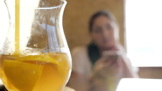 Glas-mit-einem-Cocktail-und-Stroh-auf-dem-Hintergrund-einer-jungen-Frau