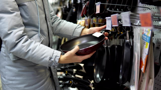 A-young-woman-chooses-a-non-stick-frying-pan-in-the-store.