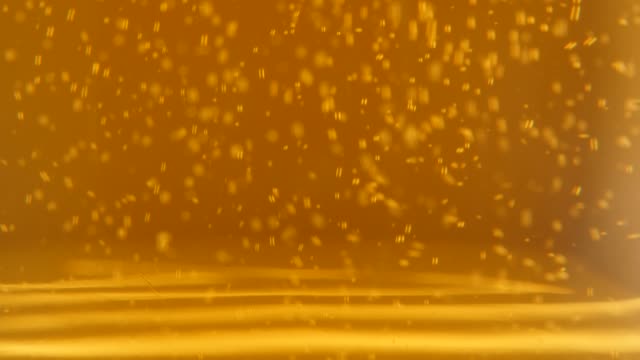 Filling-glass-with-beer-while-bubbles-and-foam-spreading-4K