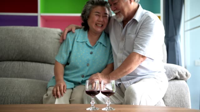 Senior-pareja-sentado-y-hablando-con-vidrio-de-vino-rojo-en-la-mesa-en-la-sala-de-estar.