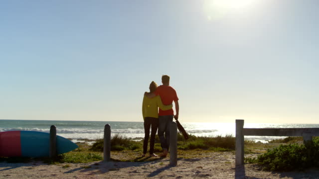 Parte-posterior-vista-pareja-joven-que-está-parado-en-la-playa-4k