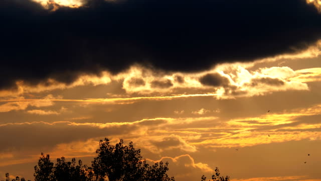 Große-rote-Sonne-bei-Sonnenuntergang-setzt-und-versteckt-sich-hinter-den-Wolken-in-den-Himmel-schweben
