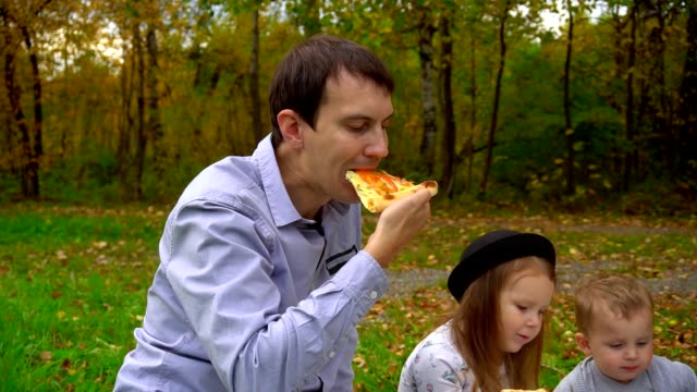 Papa-beißt-Pizza.-Picknick-im-Park-auf-dem-Rasen