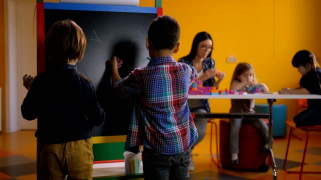 Divese-boys-drawing-at-blackboard-in-kindergarten