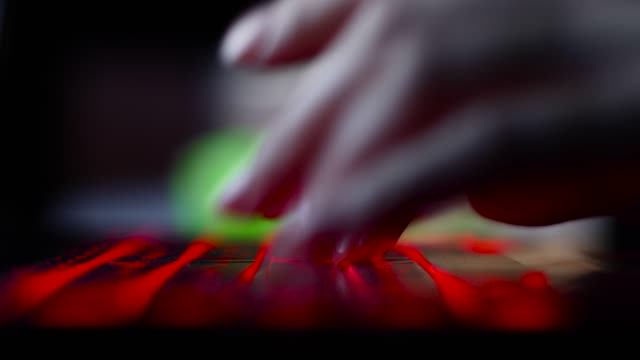 mano-de-la-chica-hacker-escribiendo-en-el-teclado-con-retroiluminación-roja