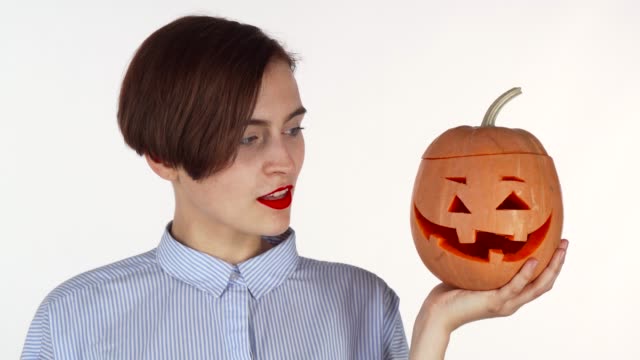 Beautiful-woman-smiling-to-the-camera,-holding-halloween-carved-pumpkin