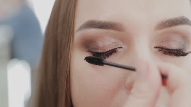 Professionelle-Make-up-Künstler-Frau-malt-Wimpern-an-Kunden-des-Schönheitssalons