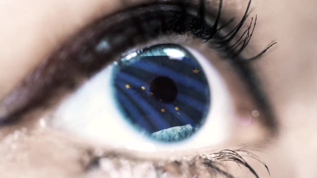 Mujer-ojo-azul-en-primer-plano-con-la-bandera-del-estado-de-Alaska-en-iris,-estados-unidos-de-América-con-movimiento-de-viento.-concepto-de-vídeo
