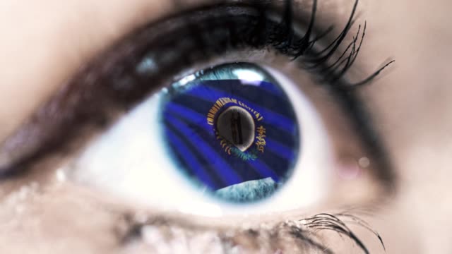 Woman-blue-eye-in-close-up-with-the-flag-of-Kentucky-state-in-iris,-united-states-of-america-with-wind-motion.-video-concept