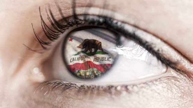 Mujer-ojo-verde-en-primer-plano-con-la-bandera-del-estado-de-California-en-iris,-estados-unidos-de-América-con-movimiento-de-viento.-concepto-de-vídeo