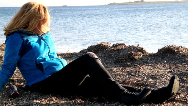 Blonde-sad-woman-sitting-at-the-seaside
