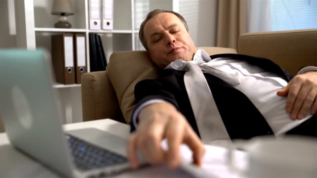 El-hombre-de-negocios-cansado-duerme-en-el-sofá-de-la-oficina