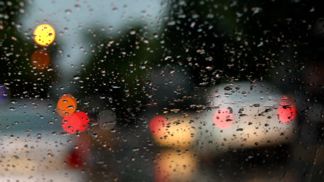 Regentropfen-auf-der-Windschutzscheibe-mit-Unschärfe-Licht-des-Fahrzeugs-auf-Stau