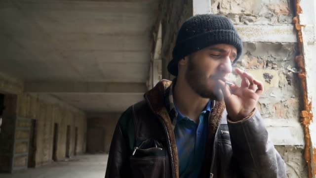 Obdachloser-Mann-raucht-Zigarette-in-verlassenen-Gebäude