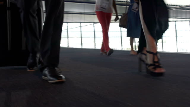 Female-and-male-legs-walking-on-carpeted-airport-floor-with-suitcase,-departure