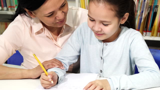 Adorable-little-girl-doing-homework-with-her-mother