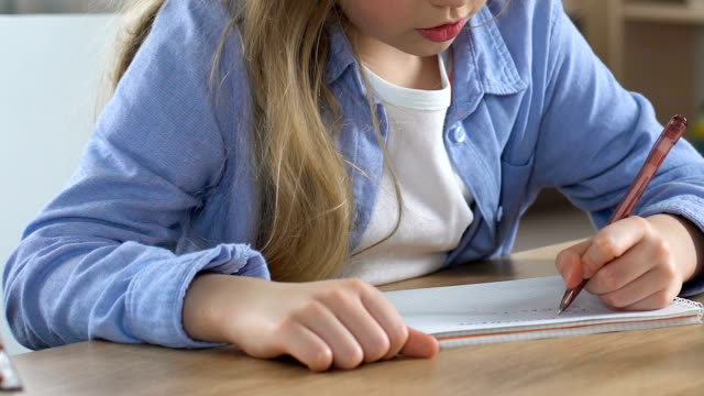 Konzentrierte-Schulmädchen-Hausaufgaben-trainieren-im-Notebook,-Hausunterricht