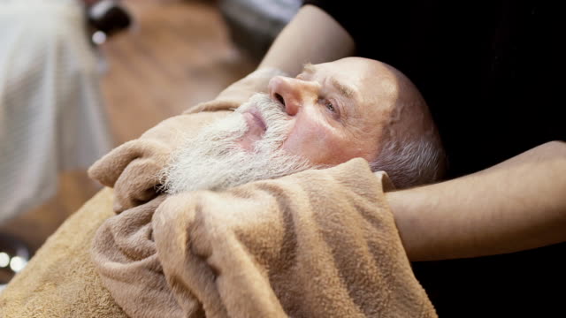 Barber-steam-up-the-face-of-mature-man-with-hot-towel-before-shaving