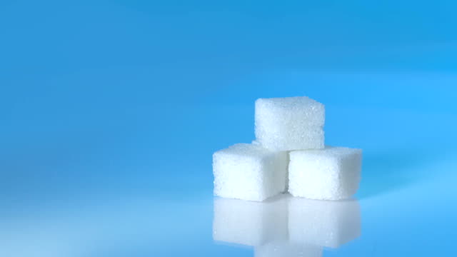 Mesa-Tiro-cubitos-de-grupo-de-azúcar-varían-de-posición-en-fondo-azul-claro