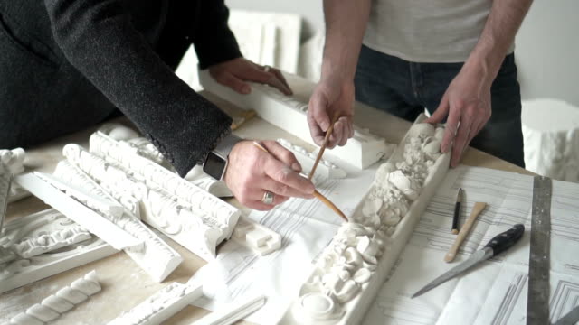 Händen-des-männlichen-Bildhauer-zeigt-Formteil-Stück-mit-Blume-ornament