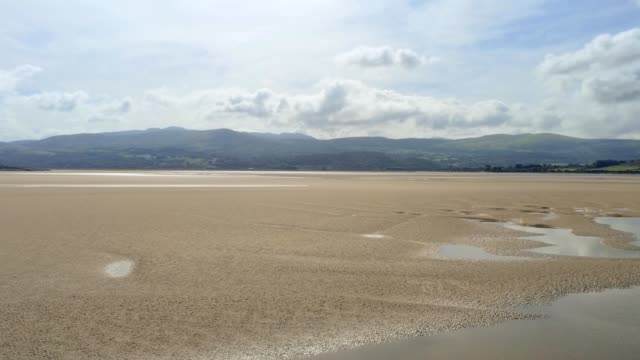 Vista-aérea,-movimiento-hacia-adelante.-Panorama-de-zángano-en-moviendo-lentamente-el-agua,-mar-y-arena-en-las-montañas-de-Snowdonia-en-país-de-Gales